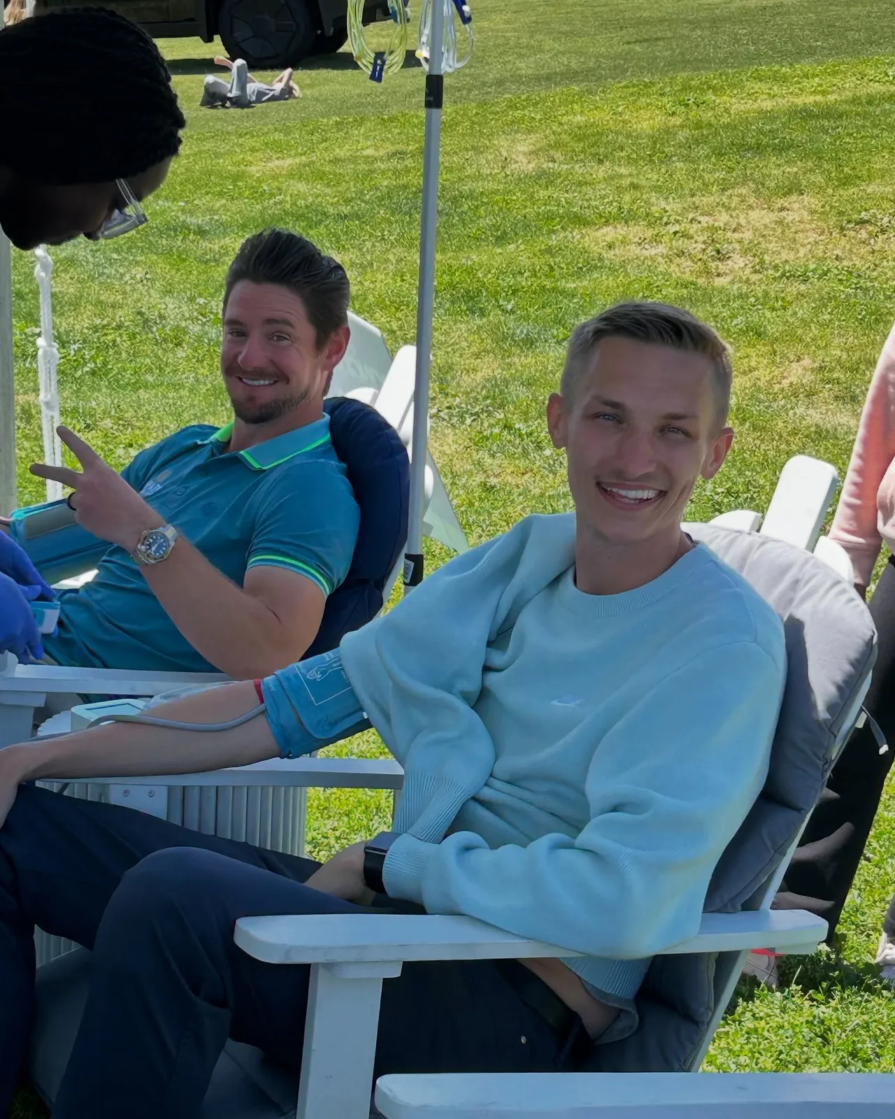Two guests smiling with their IVs under a tent on the grass