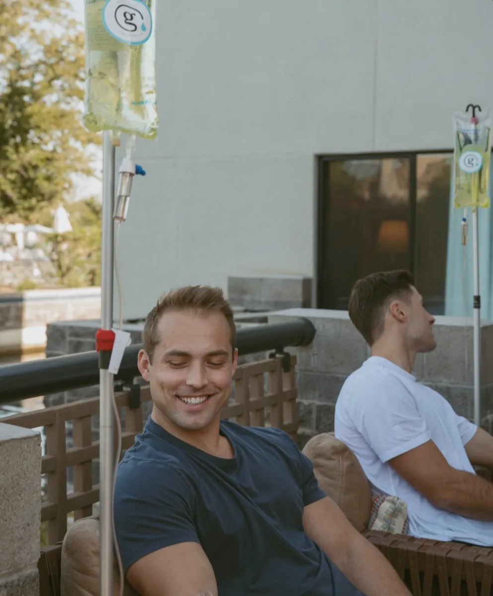 Friends laughing on a resort patio, one with an IV running